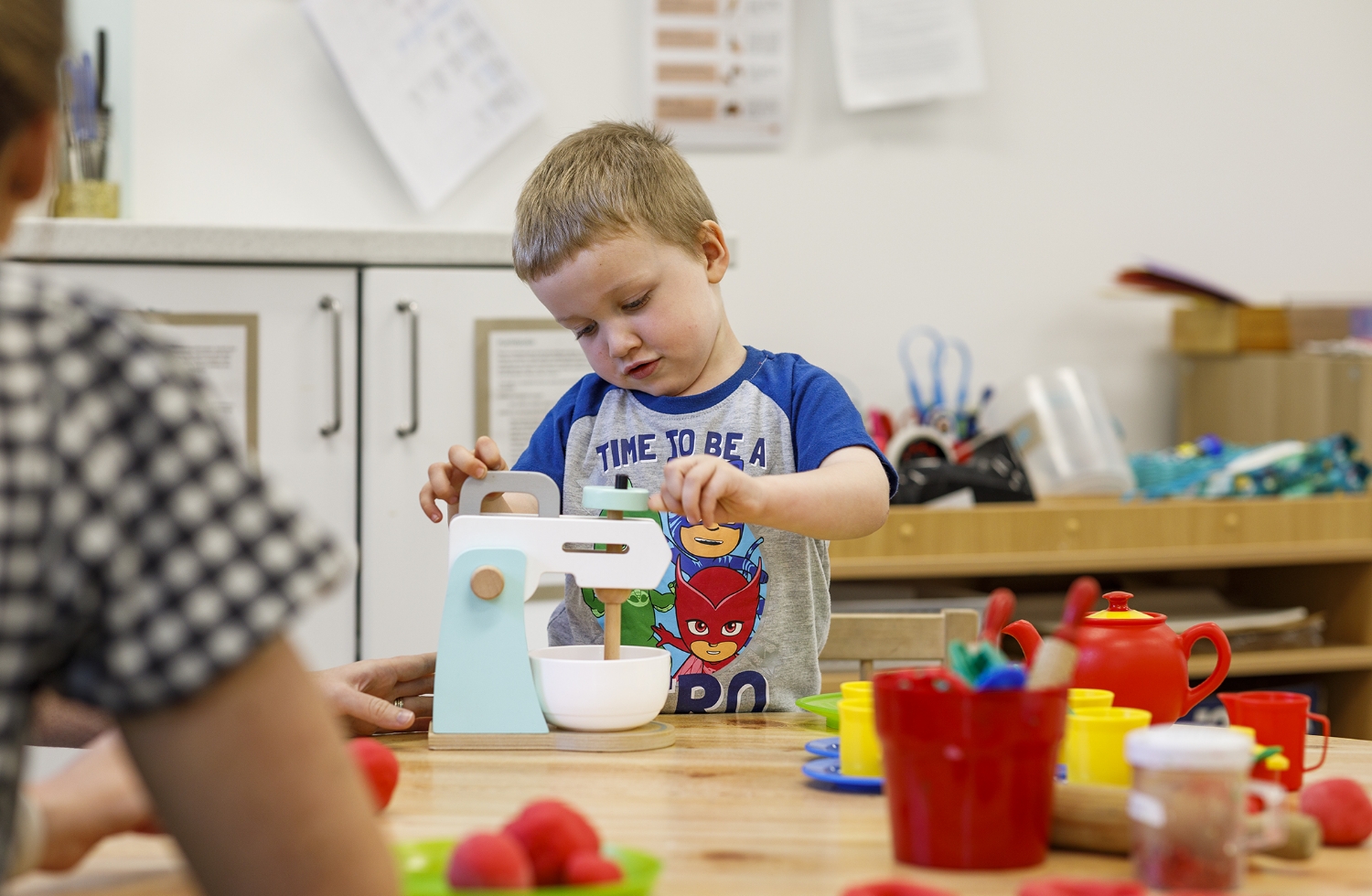 A child playing with a wooden toy cooking set.