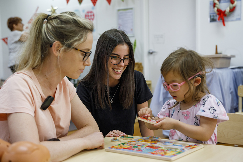 A child playing with a jigsaw puzzle with her family.