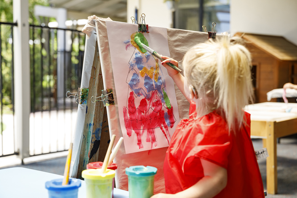 A child painting a colouring in sheet.