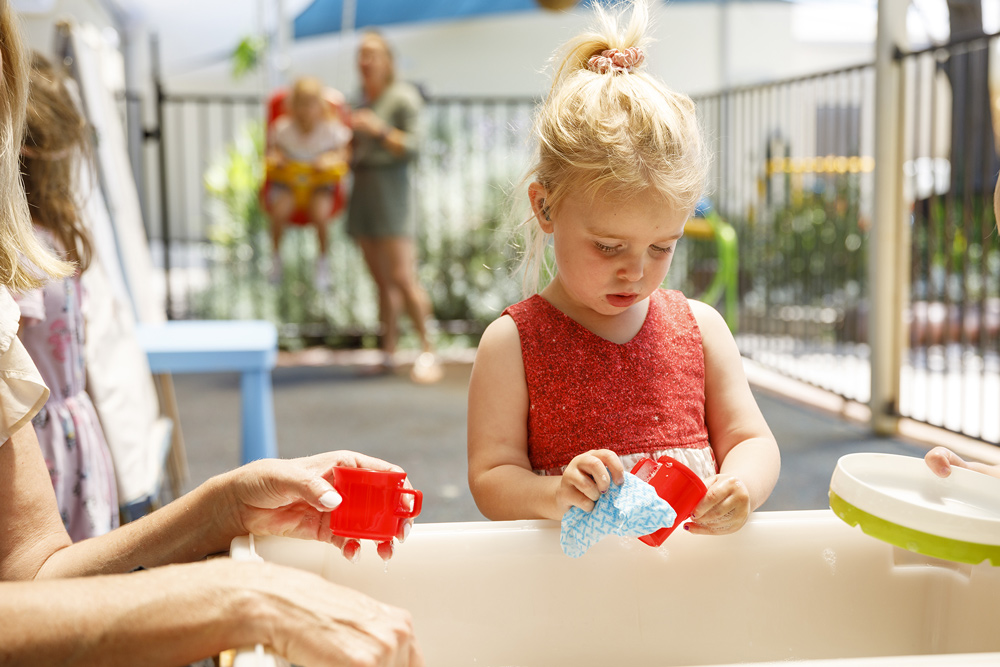 A child playing with sand and cups in a playground.