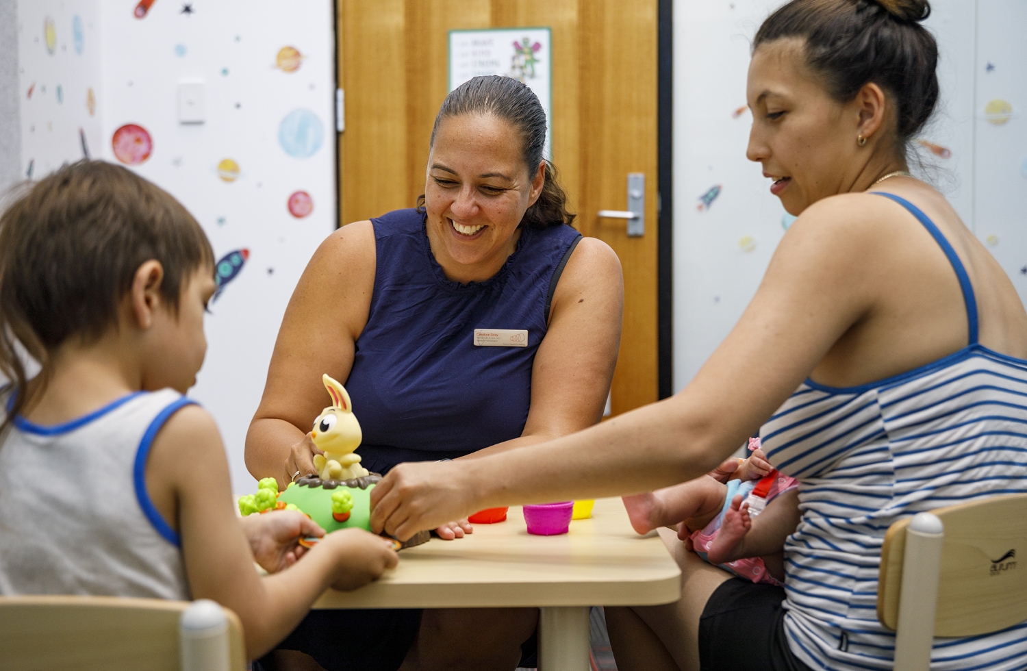 A child, mother and therapist playing with toys.