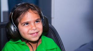 Child from Pilbara Region in green shirt receiving hearing test